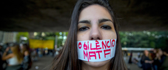 SAO PAULO,  BRAZIL - JUNE 08:   A woman marchs with a piece of tape over her mouth with a message that reads  "O silencio mata" (in English "Silence kills") during a protest against the gang rape of a 16-year-old girl  on June 8, 2016 in Sao Paulo, Brazil. In response to the assault, Brazil's interim President Michel Temer said that Brazil will set up a specialized group to fight violence against women. (Photo by Cris Faga/LatinContent/Getty Images)